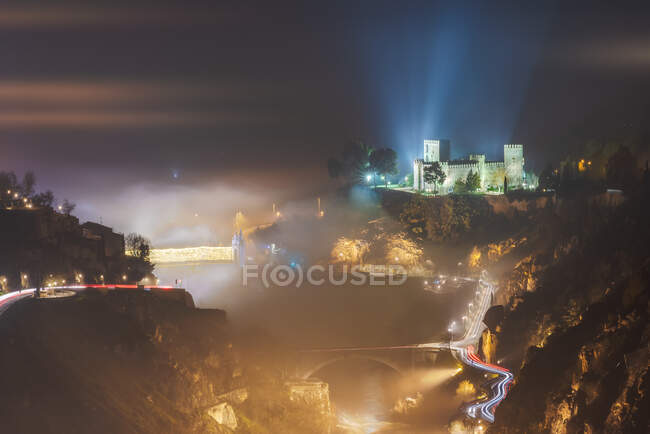 From above amazing scenery of luminous ancient castle and bridge in foggy mountain terrain in sunrise — Stock Photo