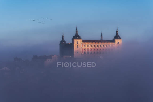 Desde arriba maravilloso paisaje de castillo medieval construido sobre la ciudad en nebuloso amanecer colorido - foto de stock
