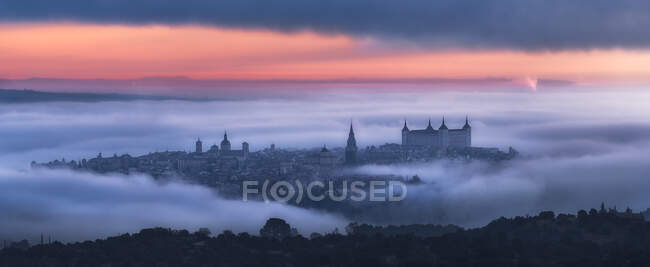 Vista aérea de la antigua ciudad y el palacio medieval del Alcázar de Toledo en la niebla en colorido amanecer - foto de stock