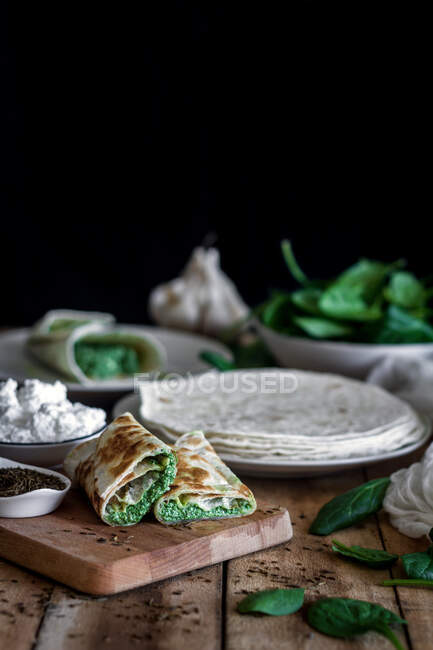 De cima de tortilla saborosa recheada com purê de espinafre em mesa de madeira com ingredientes — Fotografia de Stock