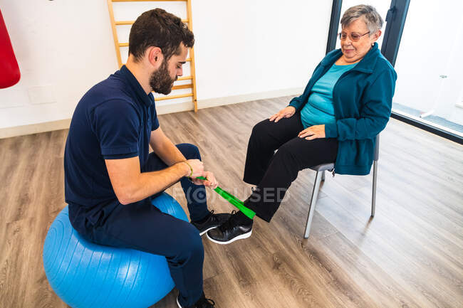 Donna anziana che pratica esercizi di resistenza con allenatore in palestra — Foto stock