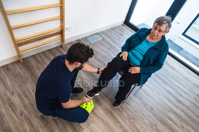Senior lady during exercise with trainer using equipment in gym — Stock Photo