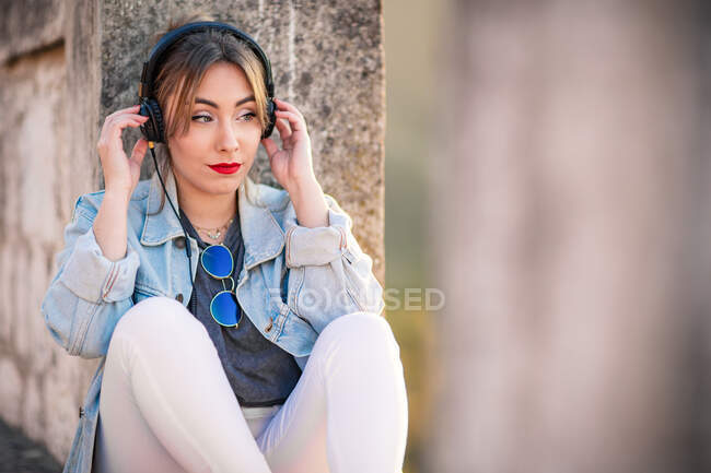 Joyful young woman in trendy casual outfit smiling and looking away on sunny day — Stock Photo