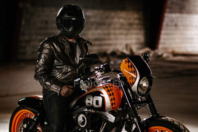 Elegante hombre sentado en su bonita motocicleta dentro de un garaje - foto de stock