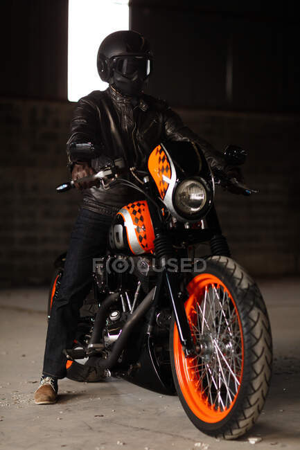 Homem elegante sentado em sua moto bonita dentro de uma garagem — Fotografia de Stock
