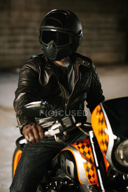 Uomo elegante seduto sulla sua bella moto all'interno di un garage — Foto stock