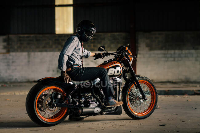 Елегантний чоловік сидить на своєму красивому мотоциклі всередині гаража — стокове фото
