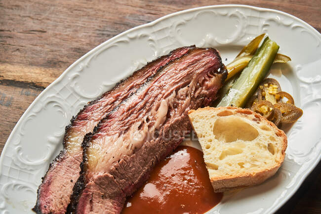 Вид сверху на кусочки мяса с куском хлеба и кетчупом на тарелке на столе — стоковое фото