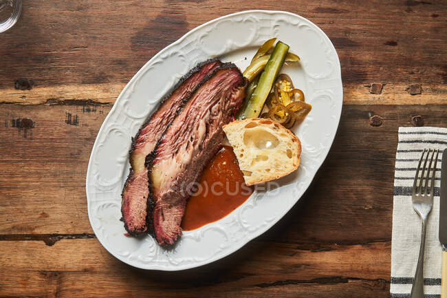 Vista dall'alto di fette di carne con pezzo di pane e ketchup sul piatto sul tavolo — Foto stock