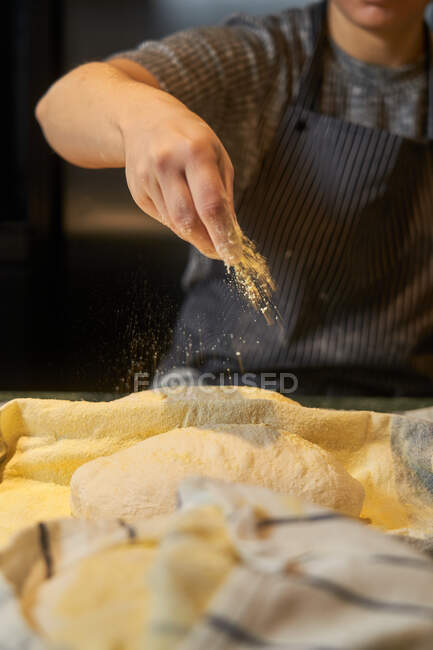 De cima de mãos femininas sem rosto amassando ramo de massa de farinha fresca à mesa na padaria — Fotografia de Stock