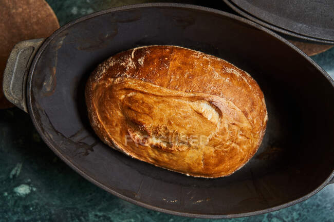 Ansicht von gekochten goldenen Brotlaiben in gusseisernen Formen auf dem Tisch — Stockfoto