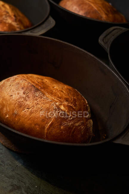 Вид зверху варених золотих хлібних хлібів у чавунних формах на столі — стокове фото