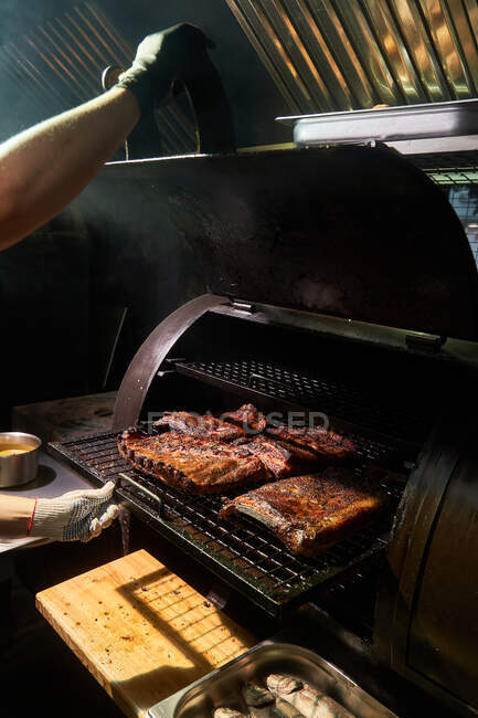 De cima do chef de colheita em luvas grelhando pedaços de carne em no rack no churrasco — Fotografia de Stock