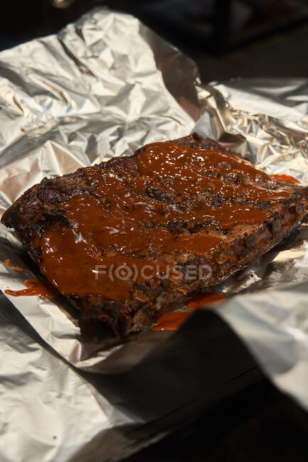 Barbecue sauce on ribs placed on kitchen foil — Stock Photo