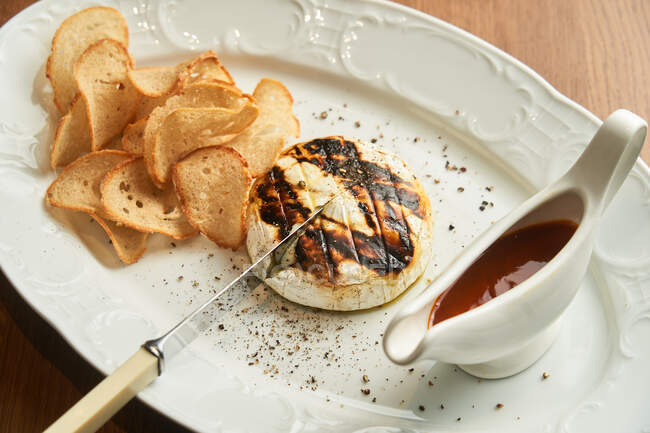 From above delicious grilled chicken burger with crispy baked bread chips and BBQ sauce on plate on table — Stock Photo