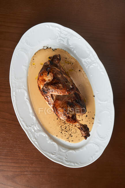 Зверху приготована смачна смажена ціла курка, що подається на білій тарілці на столі — стокове фото