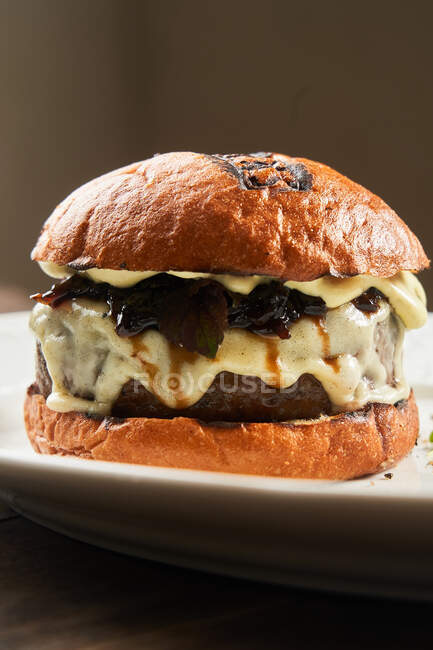 Delicioso hambúrguer de carne grelhada caseiro com queijo derretido que serve no prato na mesa — Fotografia de Stock