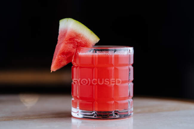 Smoothie de pastèque fraîchement sain dans une tasse en verre décorée avec un morceau de fruit sur une surface réfléchie — Photo de stock