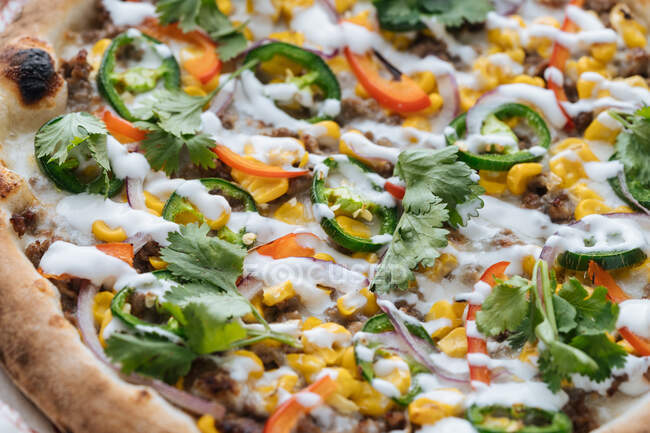 From above closeup of  tasty baked pizza with minced meat and corn decorated with bell pepper and parsley with mozzarella cheese in cafe — Stock Photo