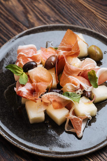 Von oben köstliche Scheiben Räucherlachs mit Gemüse und eingelegten Oliven auf dem Teller — Stockfoto