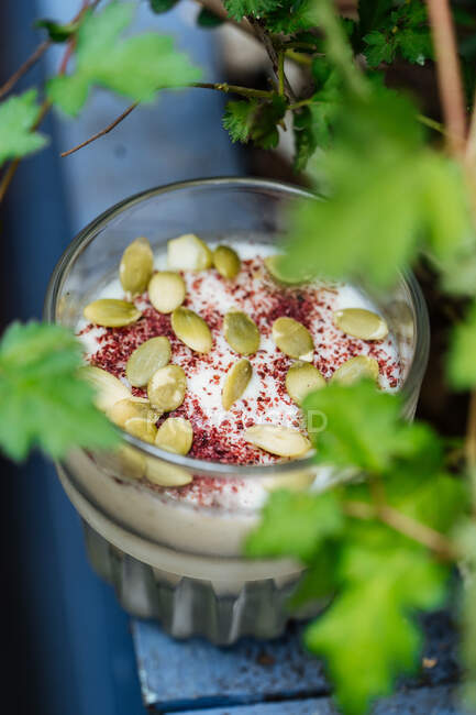Dall'alto dolce dessert cremoso con cannella e semi in tazza di vetro su superficie decorata — Foto stock