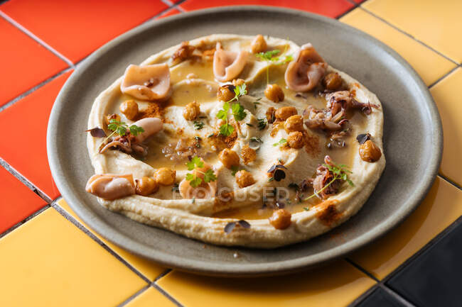 From above tasty appetizing pizza with sliced ham and chickpeas sprinkled with hers on gray plate — Stock Photo