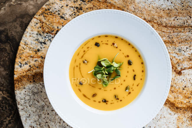 D'en haut savoureuse soupe de crème de légumes appétissante dans une assiette blanche à la table dans un café — Photo de stock