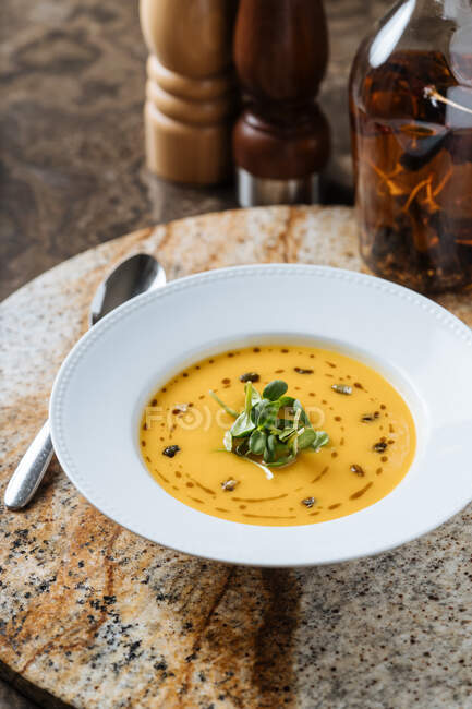 Сверху вкусный аппетитный овощной сливочный суп в белой тарелке подается с вином в бокале за столом в кафе — стоковое фото