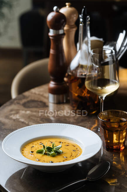 From above tasty appetizing vegetable cream soup in white plate served with wine in glass at table in cafe — Stock Photo