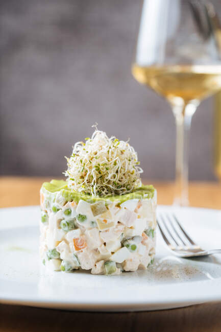Leckerer frischer Gemüsesalat mit Dekoration oben auf weißem Teller auf Holztisch serviert mit einem Glas Wein im Restaurant — Stockfoto
