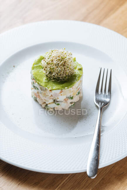 Leckerer frischer Gemüsesalat mit Dekoration oben auf weißem Teller auf Holztisch im Restaurant — Stockfoto