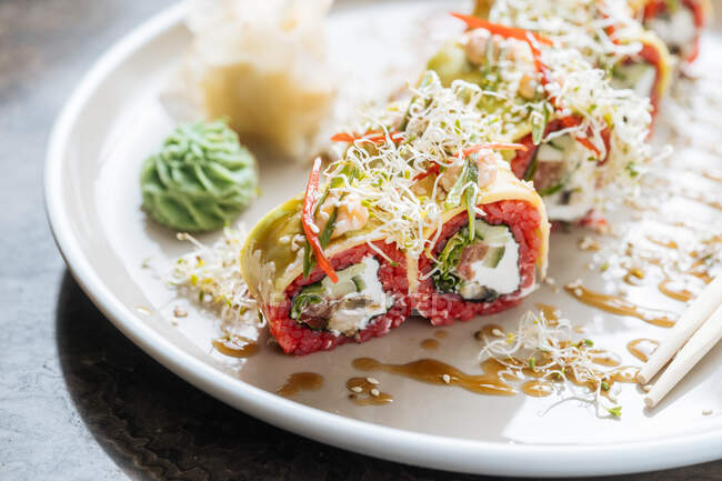 Frisches, schmackhaftes Sushi mit Gemüse auf weißem Teller auf dem Tisch — Stockfoto