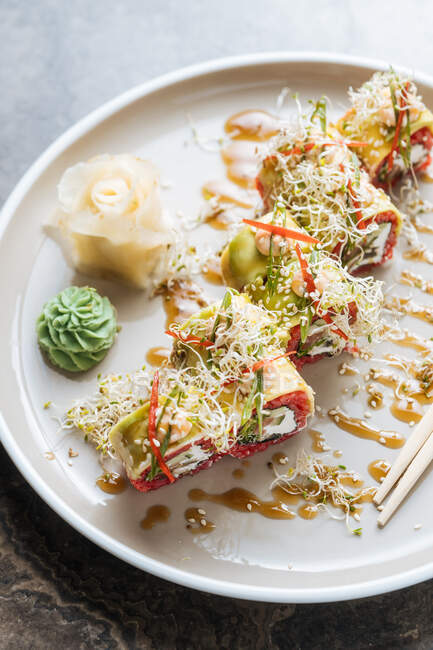 Sushi saporito fresco con verdi su piatto bianco su tavolo — Foto stock