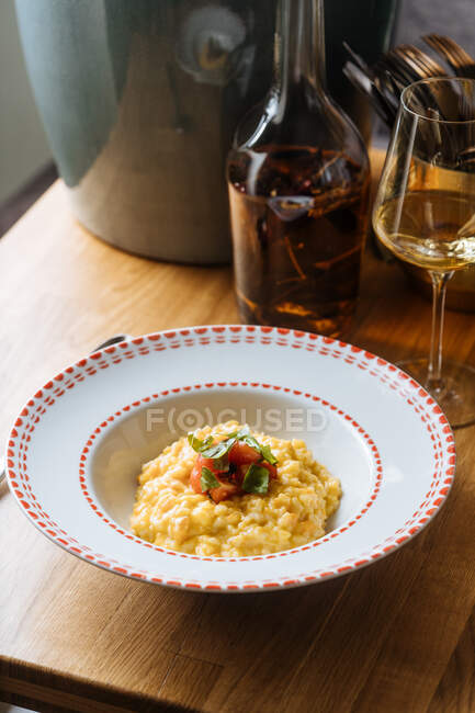 Du haut risotto appétissant à la citrouille décorée de tomates tranchées et verte dans une assiette ornementale sur la table — Photo de stock