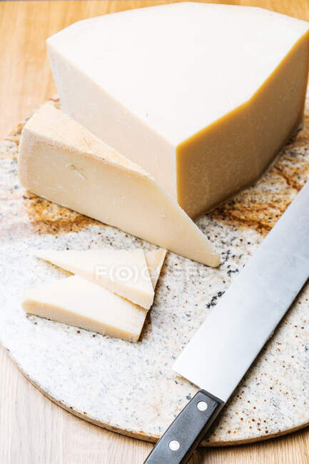 Bloco apetitoso gourmet de faca de queijo na tábua de corte na mesa — Fotografia de Stock