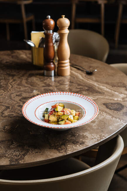 Зверху соковитий свіжий овочевий салат з томатної цвітної моркви з зеленим в декоративній білій тарілці на круглому столі в ресторані — стокове фото