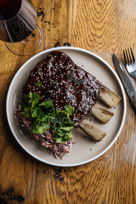 Von oben saftige, schmackhafte Rinderrippen und grüne Petersilie mit Gemüsesalat, serviert am Tisch mit Wein im Restaurant — Stockfoto