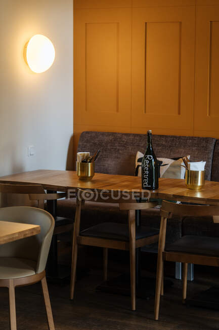 Bottiglia scura su giallo capace circondata da sedie in interno elegante di ristorante elegante con luce calda di moda lampada rotonda — Foto stock