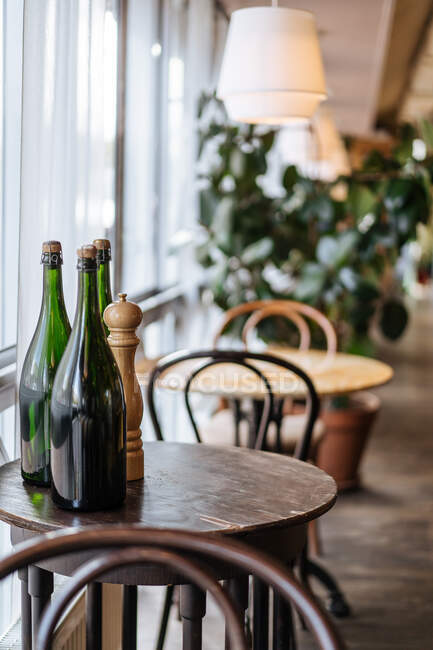 Endroit raffiné cher avec table et chaises recouvertes de lampe chaude et bouteille d'alcool dans le restaurant — Photo de stock