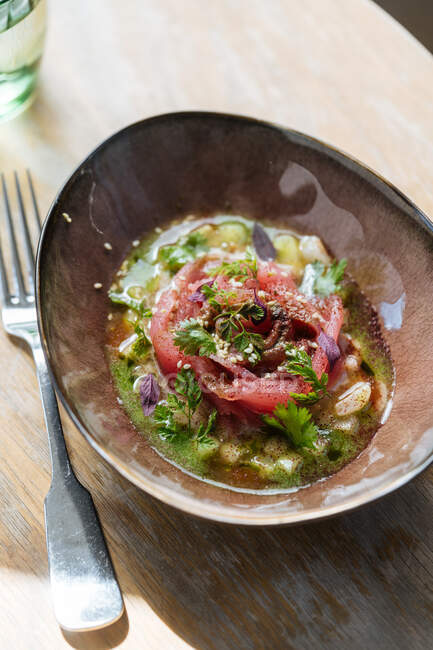 Свіжий смачний лососевий салат в соусі з зеленню на мисці на столі — стокове фото