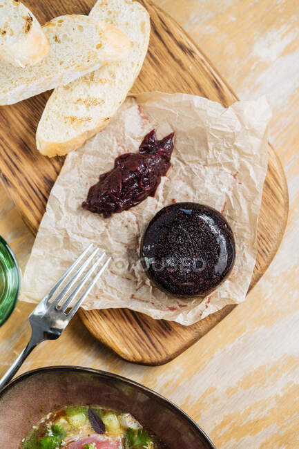 Сверху аппетитное коричневое желе с ягодным соусом на выпечке бумаги на деревянном стенде на столе — стоковое фото