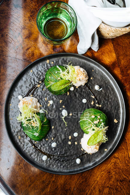 Сверху аппетитная брюссельская капуста со сливочным соусом и травами на черной тарелке в ресторане — стоковое фото