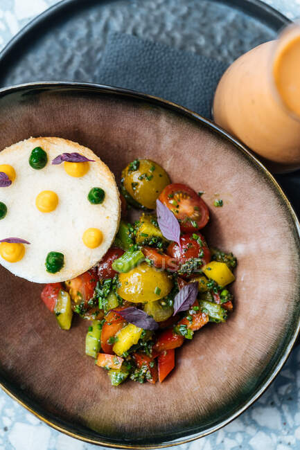 Dall'alto pomodori maturi rossi affettati cipolla pepe erbe in piatto di ceramica sul tavolo nel ristorante — Foto stock