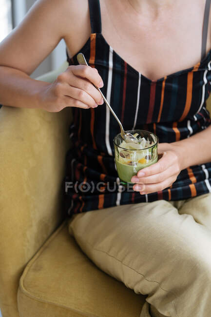 Зверху врожаю жінка насолоджується десертом і їсть желе з ложкою зі скла в кафе — стокове фото