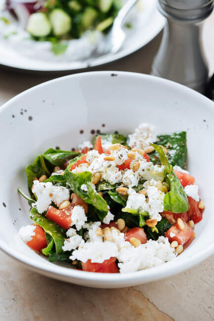 D'en haut salade appétissante juteuse de tomates rouges tranchées mûres graines vertes et fromage dans une assiette blanche au restaurant — Photo de stock