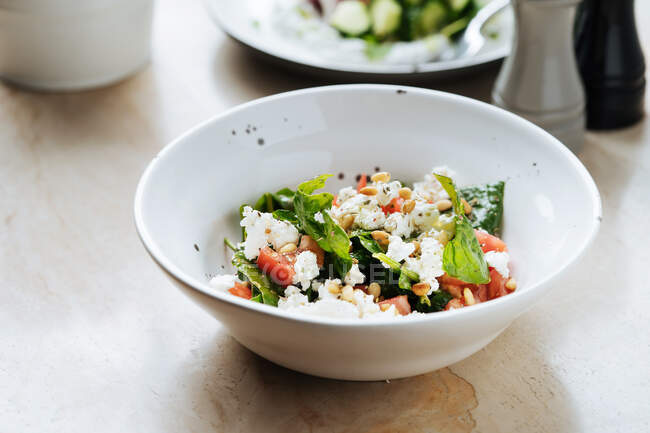Von oben saftige appetitliche Salat von reifen roten geschnittenen Tomaten grünen Samen und Käse in weißem Teller im Restaurant — Stockfoto