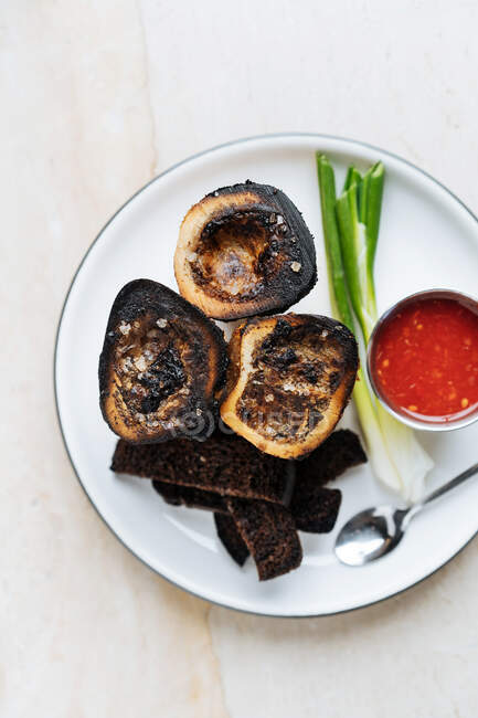 Top view of smoked rounded slices of eggplant on white plate with red sauce green onion and fried croutons of rye bread in restaurant — Stock Photo