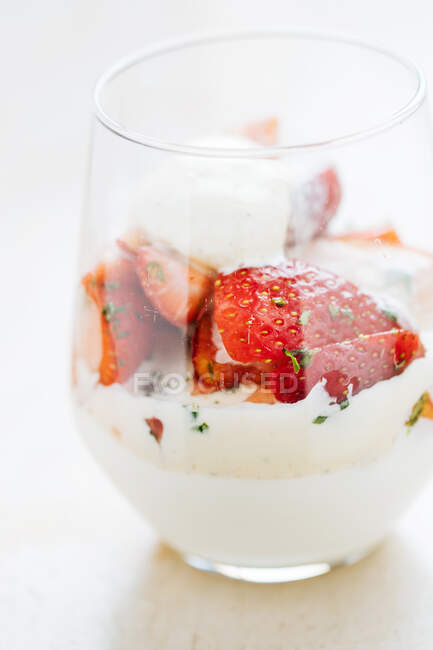 From above of glass with vanilla ice cream and pieces of fresh strawberry on table in restaurant — Stock Photo