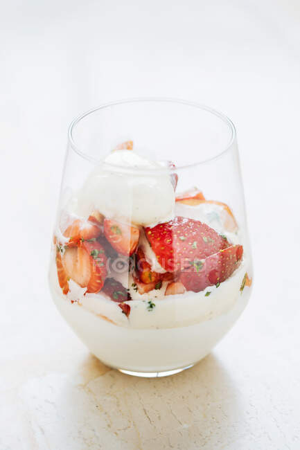 Du dessus de verre avec crème glacée vanille et des morceaux de fraise fraîche sur la table dans le restaurant — Photo de stock