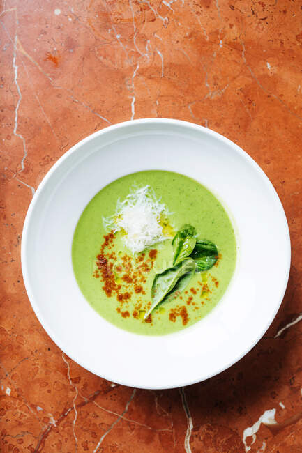 From above of cream soup of broccoli in white bowl with leaves of fresh basil and spices in restaurant — Stock Photo